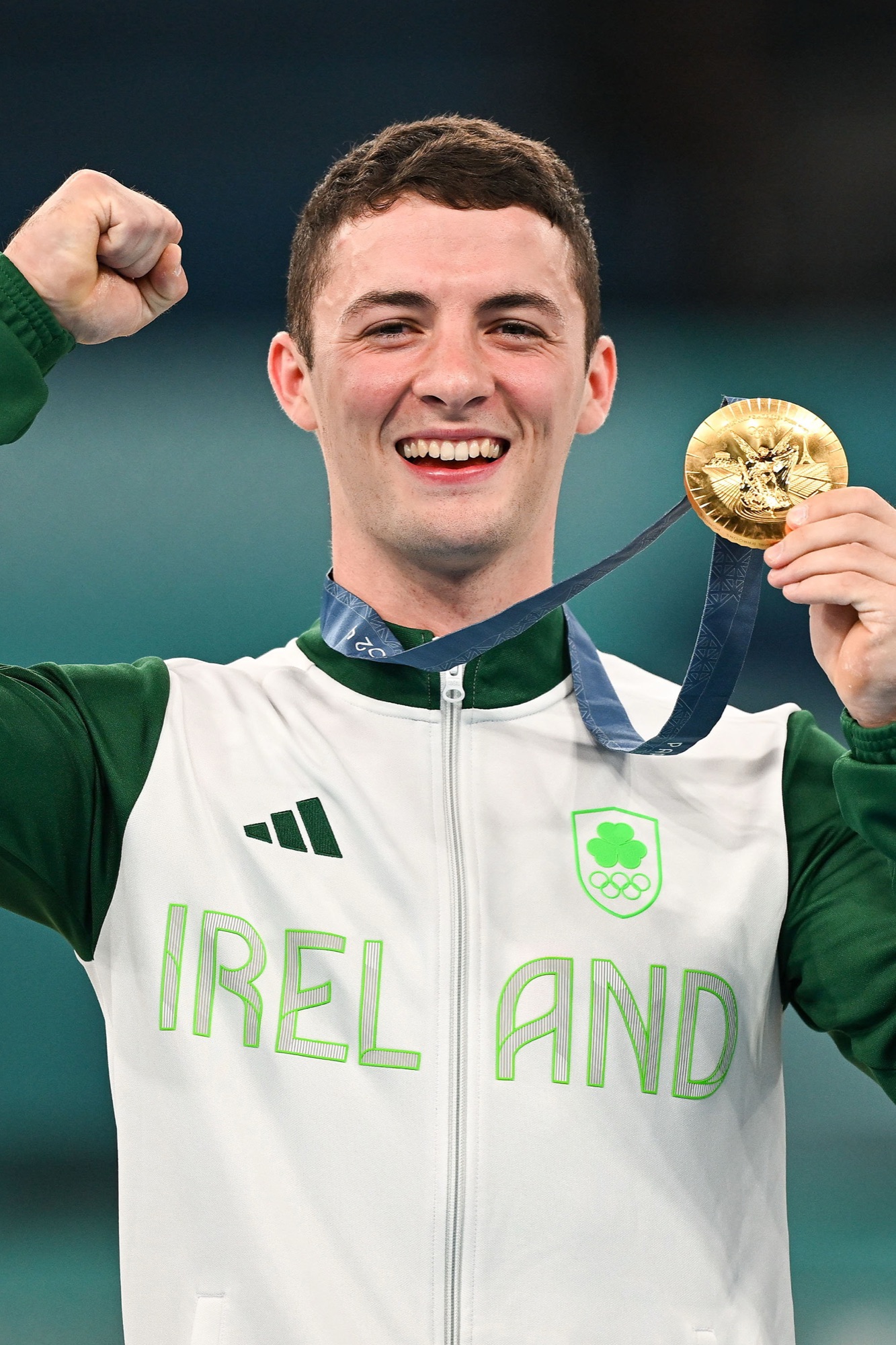 Rhys McClenaghan holding up his Olympic gold medal